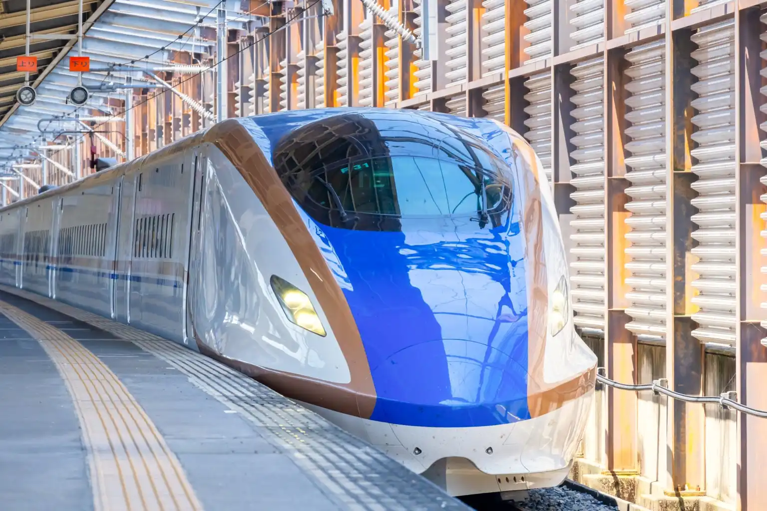 A blue and white Shinkansen at a station