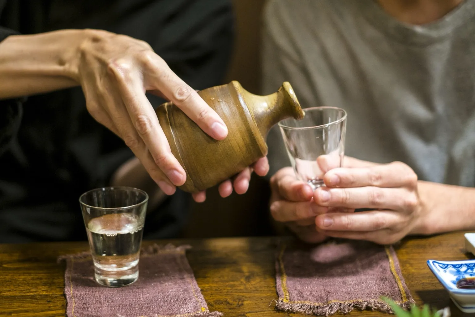 Sake poured from a ceramic flask into a glass
