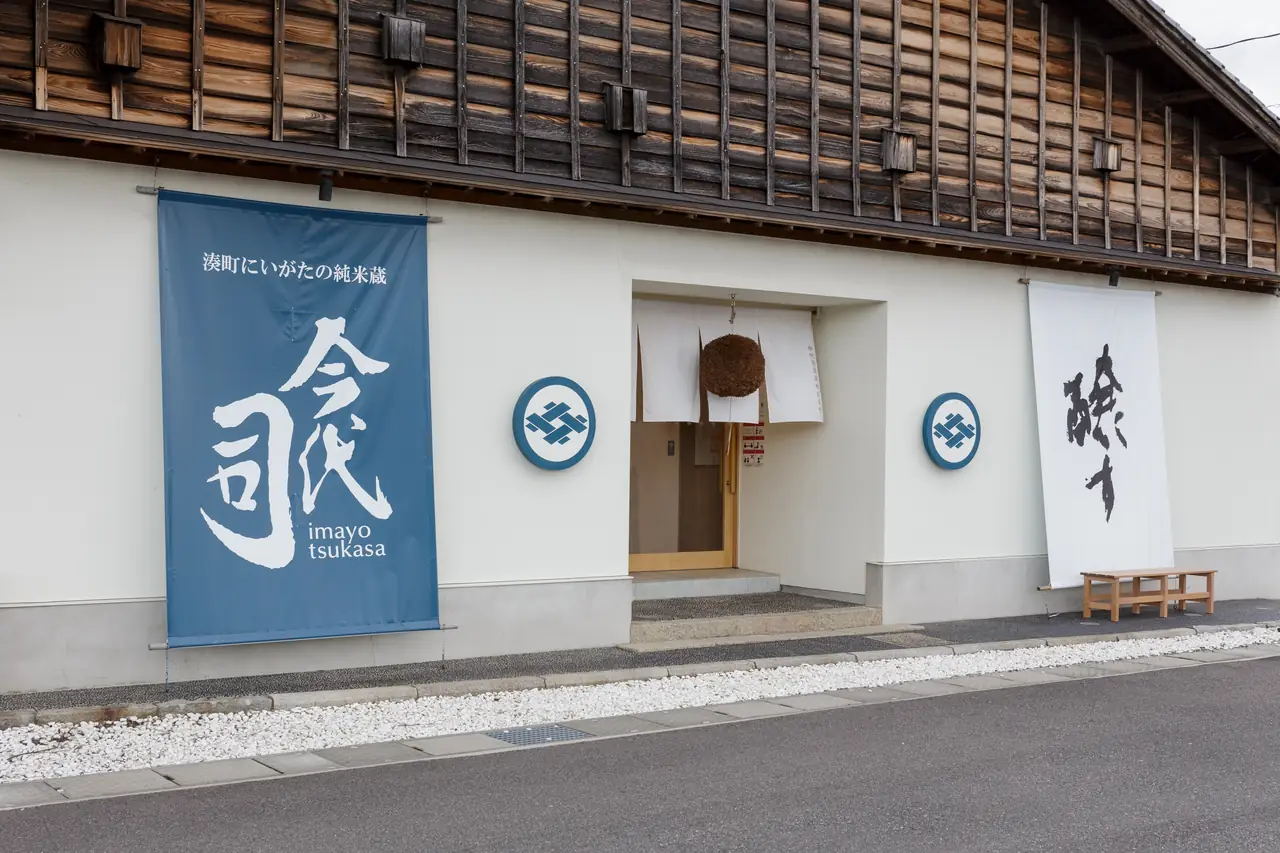 Entrance to Imayo Tsukasa sake brewery with a blue banner and wooden upper facade