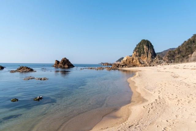 A sandy beach and rock formations along the Sasagawa Nagare coast in Murakami.