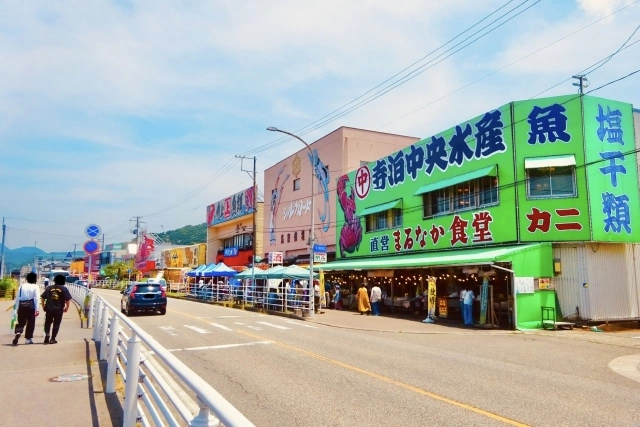 Colourful seafood shops line Teradomari Fish Market Street beside the coastal road.
