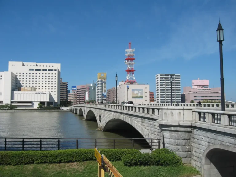 Bandai Bridge crosses the Shinano River in Niigata, with its stone-faced arches and city buildings beyond.