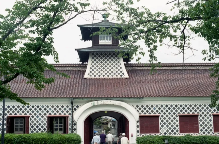 The Old Niigata Customs House, with a red tiled roof, white lattice-pattern walls and a central tower, viewed from the front.
