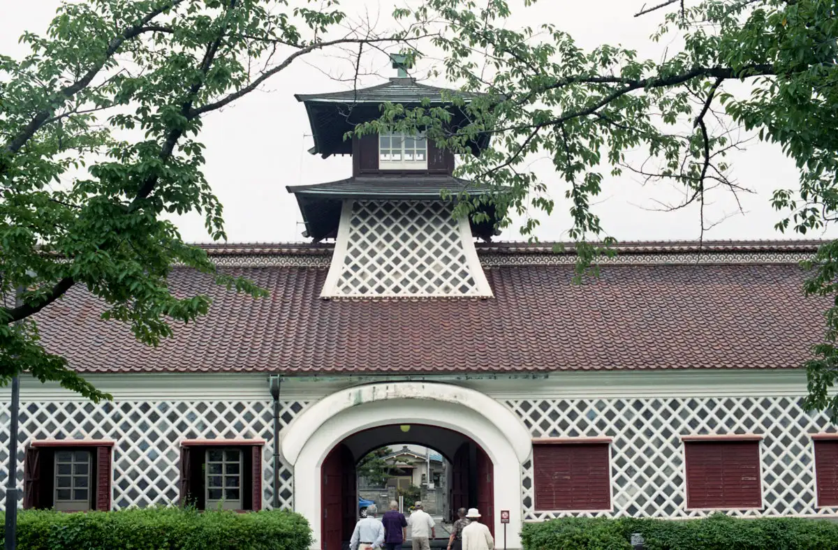 The Old Niigata Customs House, with a red tiled roof, white lattice-pattern walls and a central tower, viewed from the front.