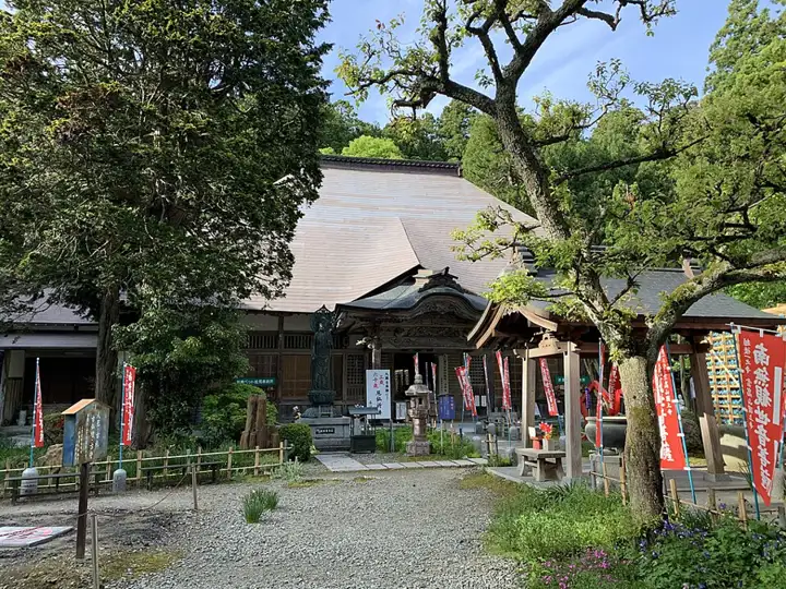 A leafy courtyard and wooden main hall at Kokujouji Temple in Tsubame