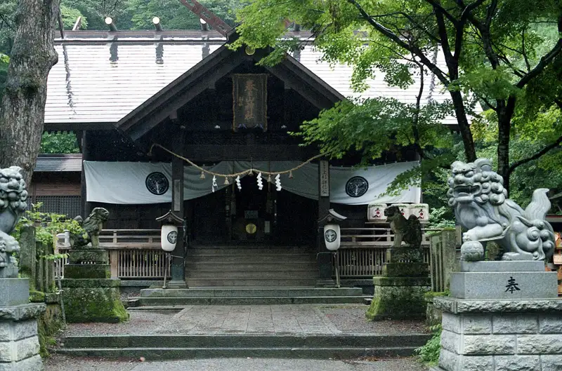 Kasugayama Shrine framed by green trees and stone guardians