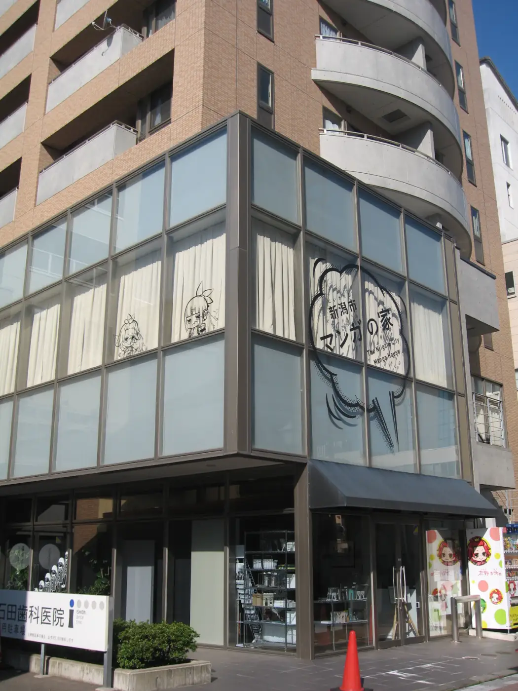 Street-level view of Niigata Manga House in a multi-storey building, with manga character illustrations visible on the upper windows.