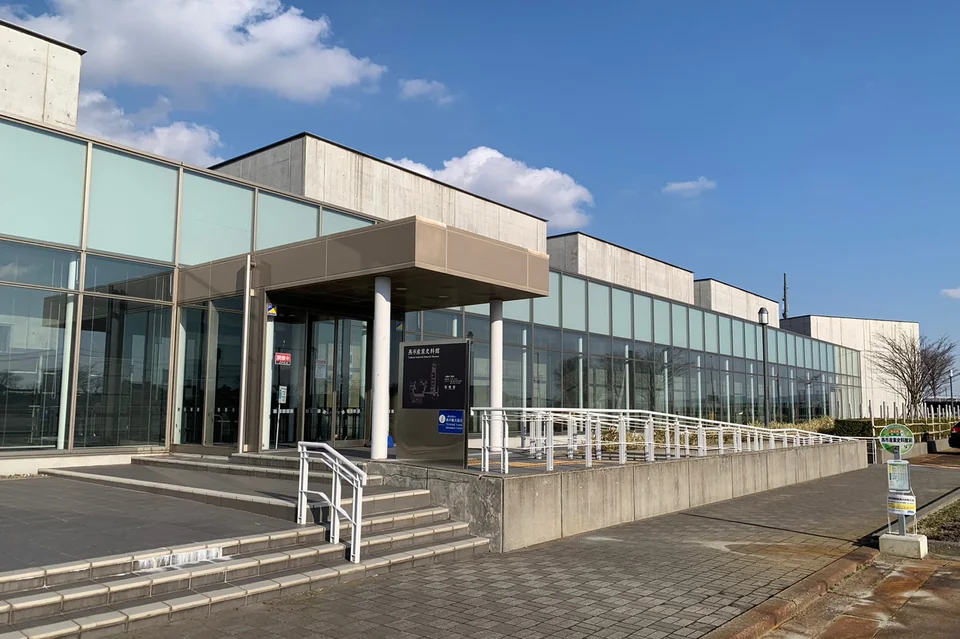 Glass-fronted entrance of the Tsubame Industrial Museum beneath a blue sky.