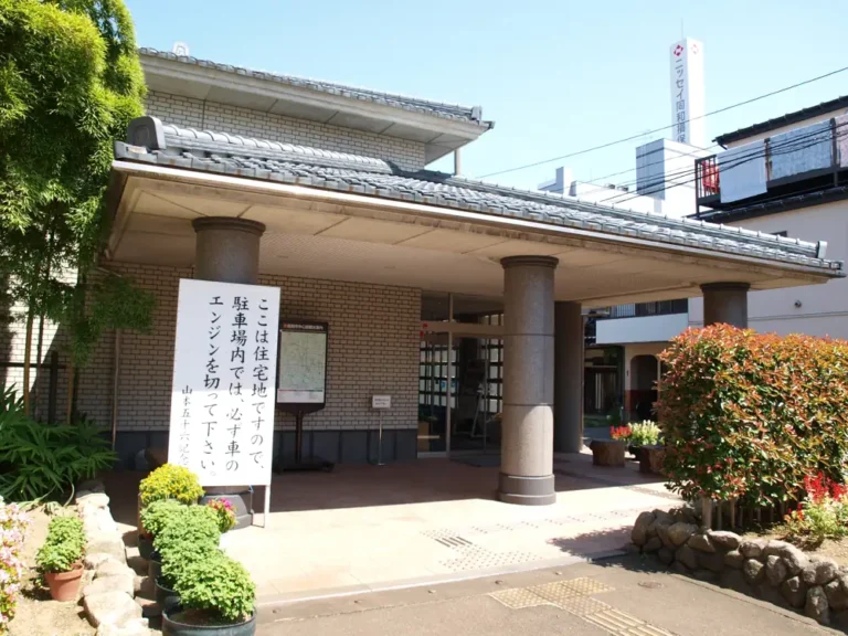 The low tiled entrance, stone columns and planted forecourt of Yamamoto Isoroku Memorial Museum.